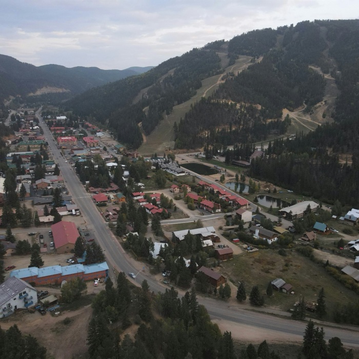 A small American mountain town spread along a main street in a wooded valley under overcast sky.